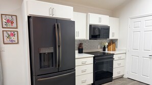 A modern kitchen with white cabinetry, a black refrigerator, a microwave, and a built-in oven. - Spacious 4-bedroom house in  Ray City close to Moody Air Force Base and Valdosta (Ray City)