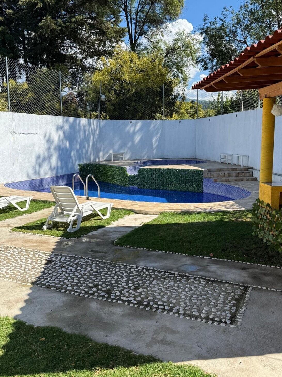 Un jardin avec une piscine, un patio couvert et un petit potager.
