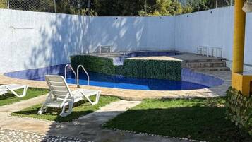 Un jardin avec une piscine, un patio couvert et un petit potager.