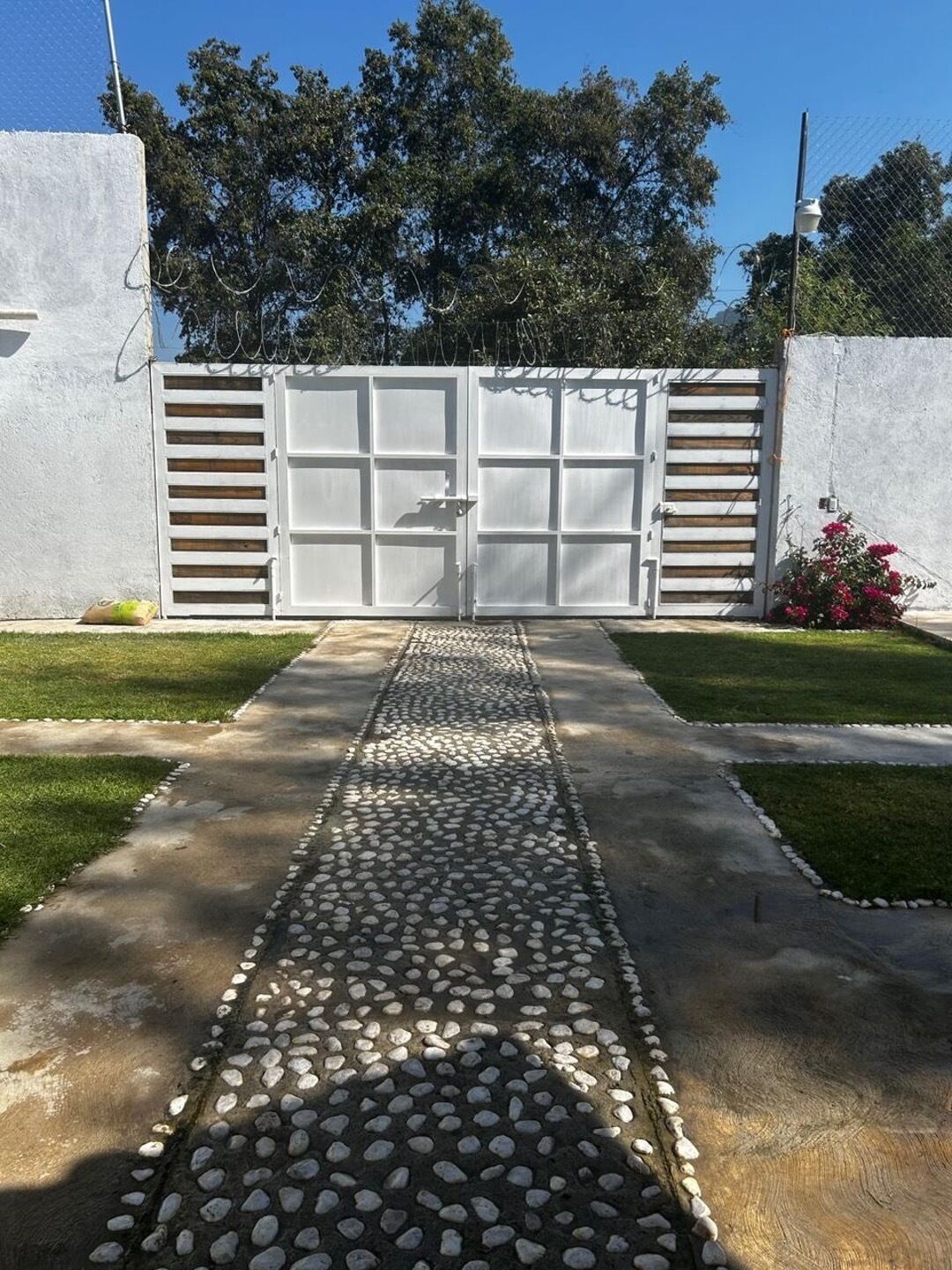 Une entrée fermée par un portail, avec un chemin pavé menant à un bâtiment.