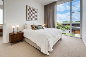 A bedroom with a large bed, two bedside tables, a view of the outdoors, and a framed artwork on the wall. - Villa Laya, Palm Beach (Palm Beach)