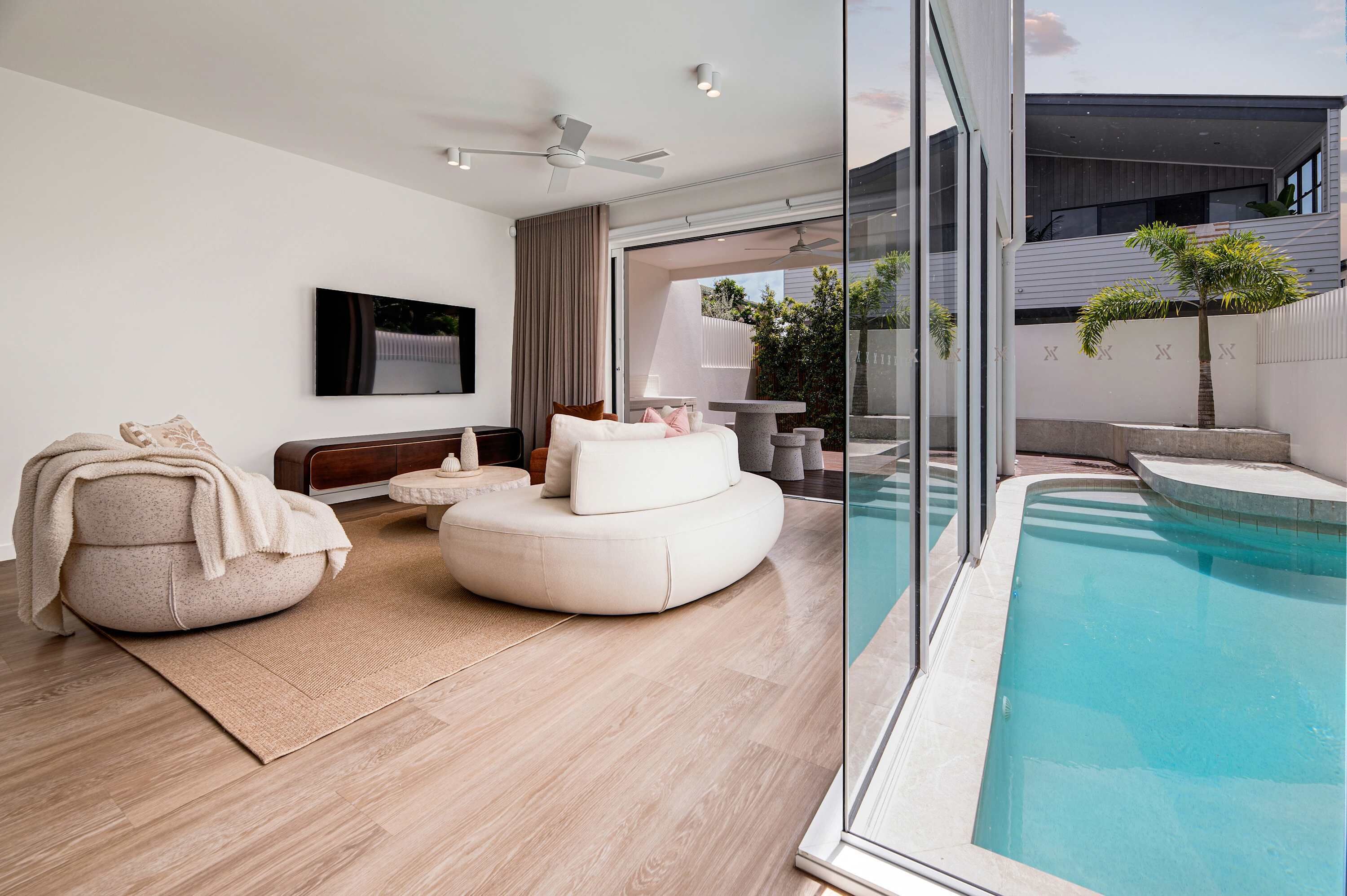 A modern living room with a pool, a sofa, a rug, and a ceiling fan.