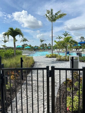 A pool area with lounge chairs and palm trees. - Cozy 2-bedroom condo in gorgeous Wellen Park Golf and Country Club (Venice)
