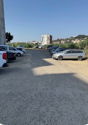 Un parking avec plusieurs voitures et un bâtiment en arrière-plan.