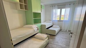 Een kamer met stapelbedden, een raam met gordijnen en een plafondlamp.