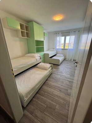 Ein Zimmer mit Etagenbetten, einem Fenster mit Vorhängen und einer Deckenleuchte.
