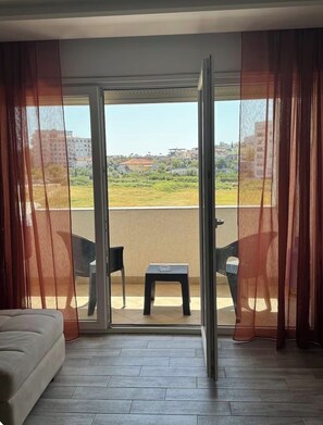 A room with a sliding glass door leading to an outdoor area with a table and chairs. - Spacious Family Stay in Astir, Tirana • Sleeps 6+ (Kashar)