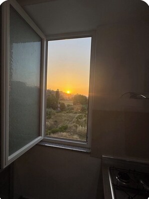 Une cuisine avec une fenêtre donnant sur un paysage au coucher du soleil.