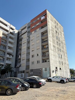 A multi-story residential building with balconies, parked cars, and a clear sky. - Spacious Family Stay in Astir, Tirana • Sleeps 6+ (Kashar)