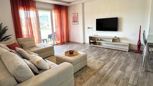 Een moderne woonkamer met een bank, een salontafel en een flatscreen televisie aan de muur.