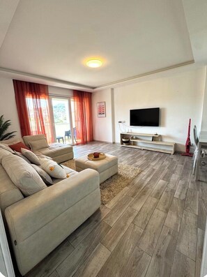 Ein modernes Wohnzimmer mit einer Couch, einem Couchtisch und einem an der Wand befestigten Flachbildfernseher.