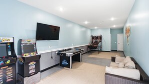 A room with a pool table, arcade machines, a TV, and a lounge area with a sofa. - Modern 3BR condo with Pool & Private garage (Wildwood)