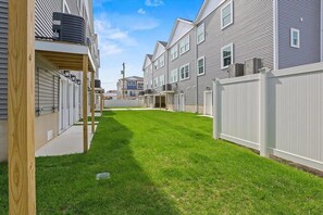 A residential area with a well-maintained lawn, a wooden deck, and a white fence. - Modern 3BR condo with Pool & Private garage (Wildwood)