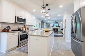 Una cocina moderna con armarios blancos, electrodomésticos de acero inoxidable y una isla central.