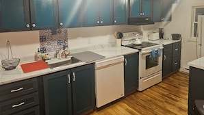 A kitchen with dark cabinets, a white countertop, and a wooden floor.