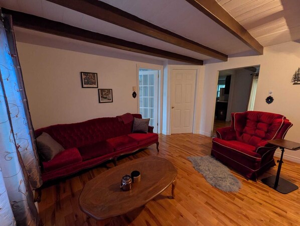 Una sala de estar con un sofá rojo, un sillón rojo y una mesa de centro de madera.