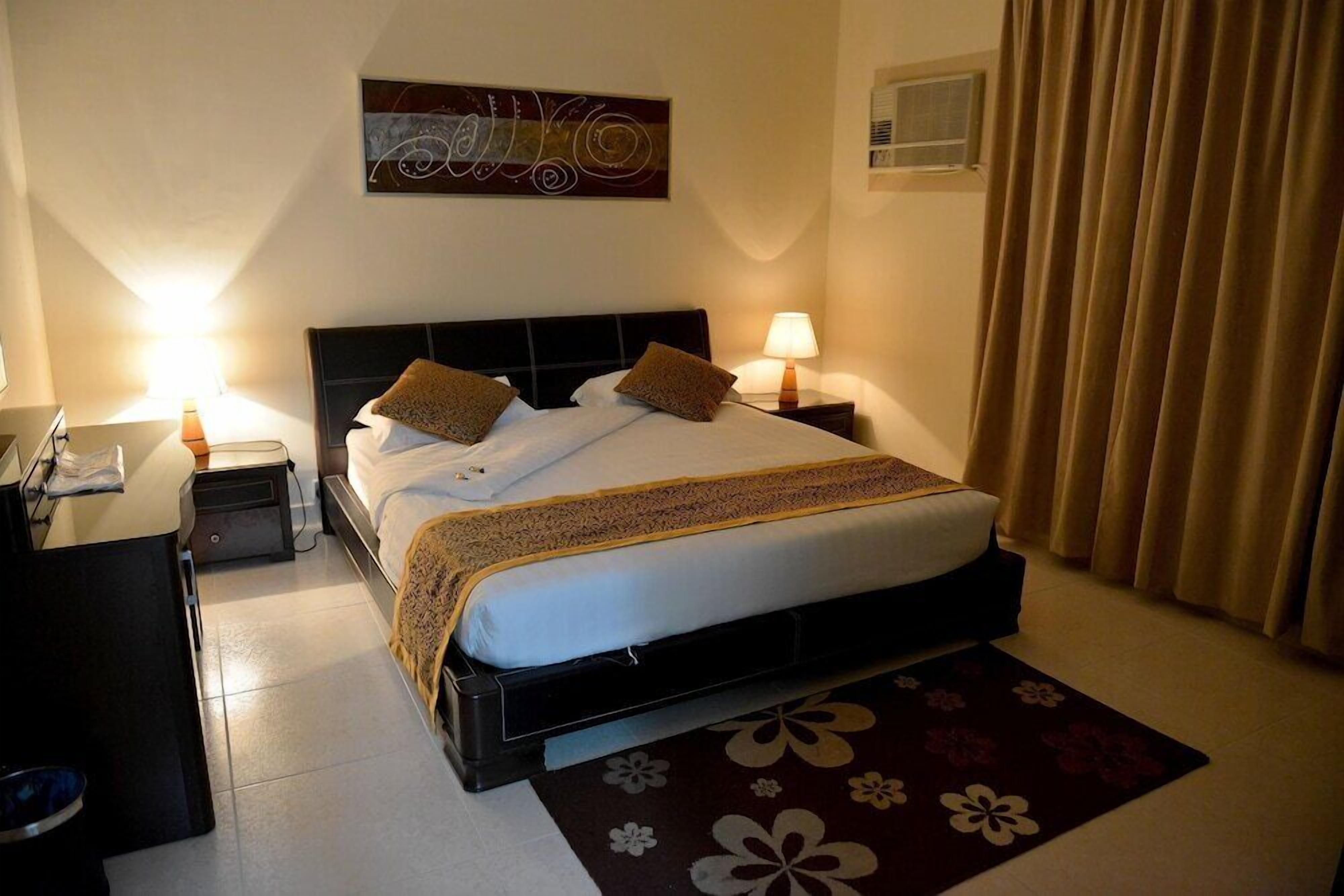 Ein Hotelzimmer mit Bett, Nachttischen, Schreibtisch und Lampe.