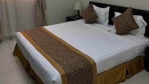 Habitación de hotel con cama, cortinas, mesita de noche, lámpara y aire acondicionado instalado en la pared.