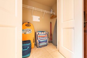 A hallway with a surfboard, a striped bag, and a broom. - KLVR Presents Honua Kai Hokulani 1034 Penthouse (Lahaina)
