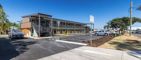 A motel with a two-story structure, a covered parking area, and a sign indicating guest parking.
