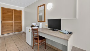 A compact room with a desk, chair, a flat-screen TV, a small refrigerator, and a wooden wardrobe. - Black Nugget Hotel (Moranbah)