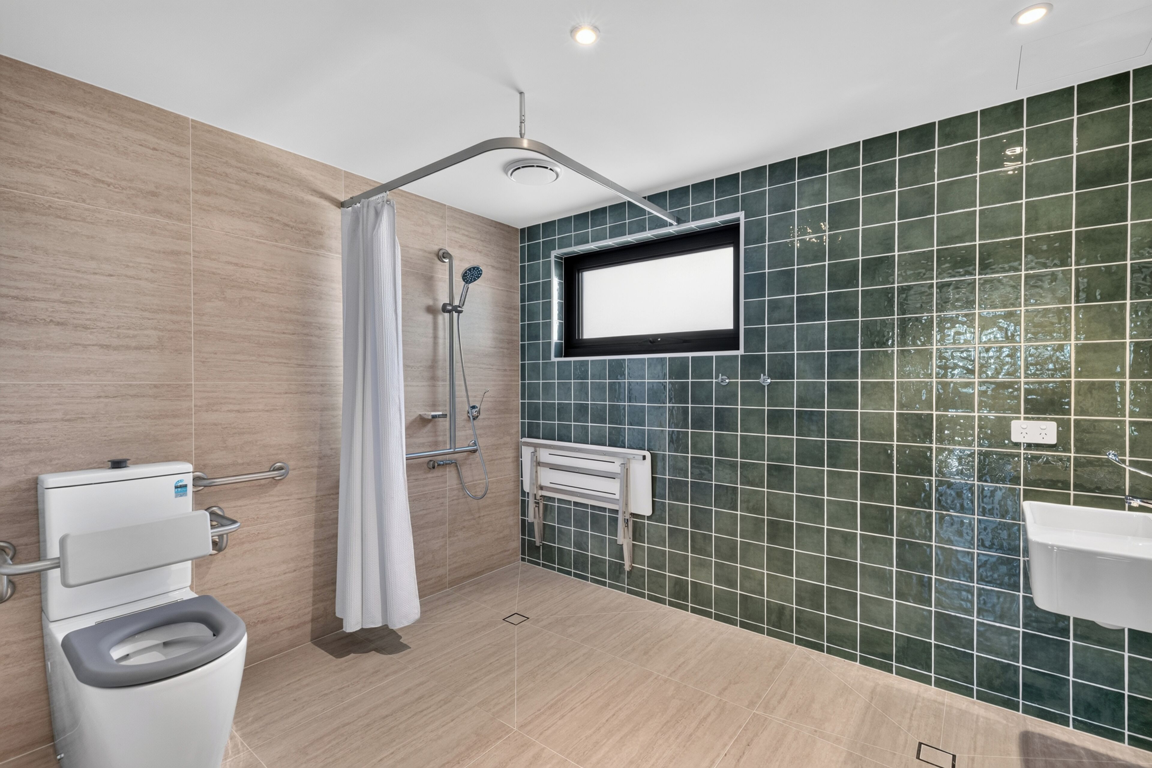 A modern bathroom with a shower, toilet, and sink.