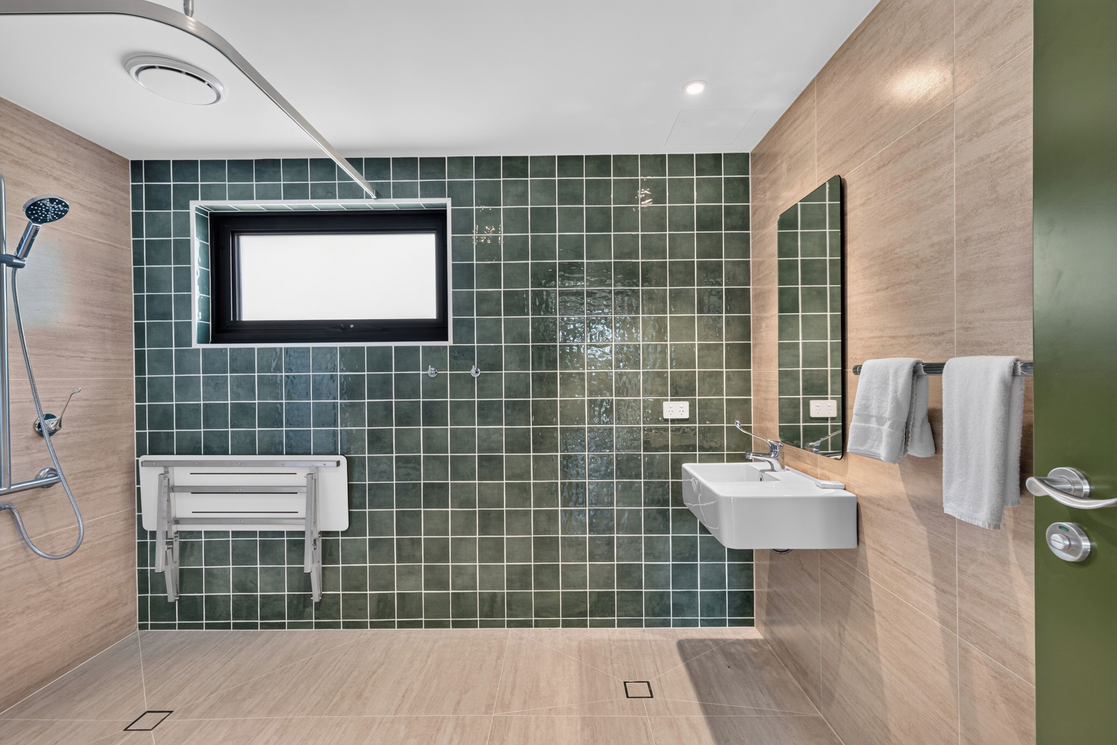 Un baño moderno con ducha, lavamanos y espejo.