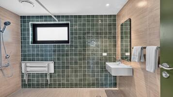 Un baño moderno con ducha, lavamanos y espejo.