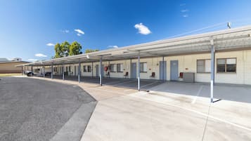 A motel with a covered parking area, numbered rooms, and a service truck.