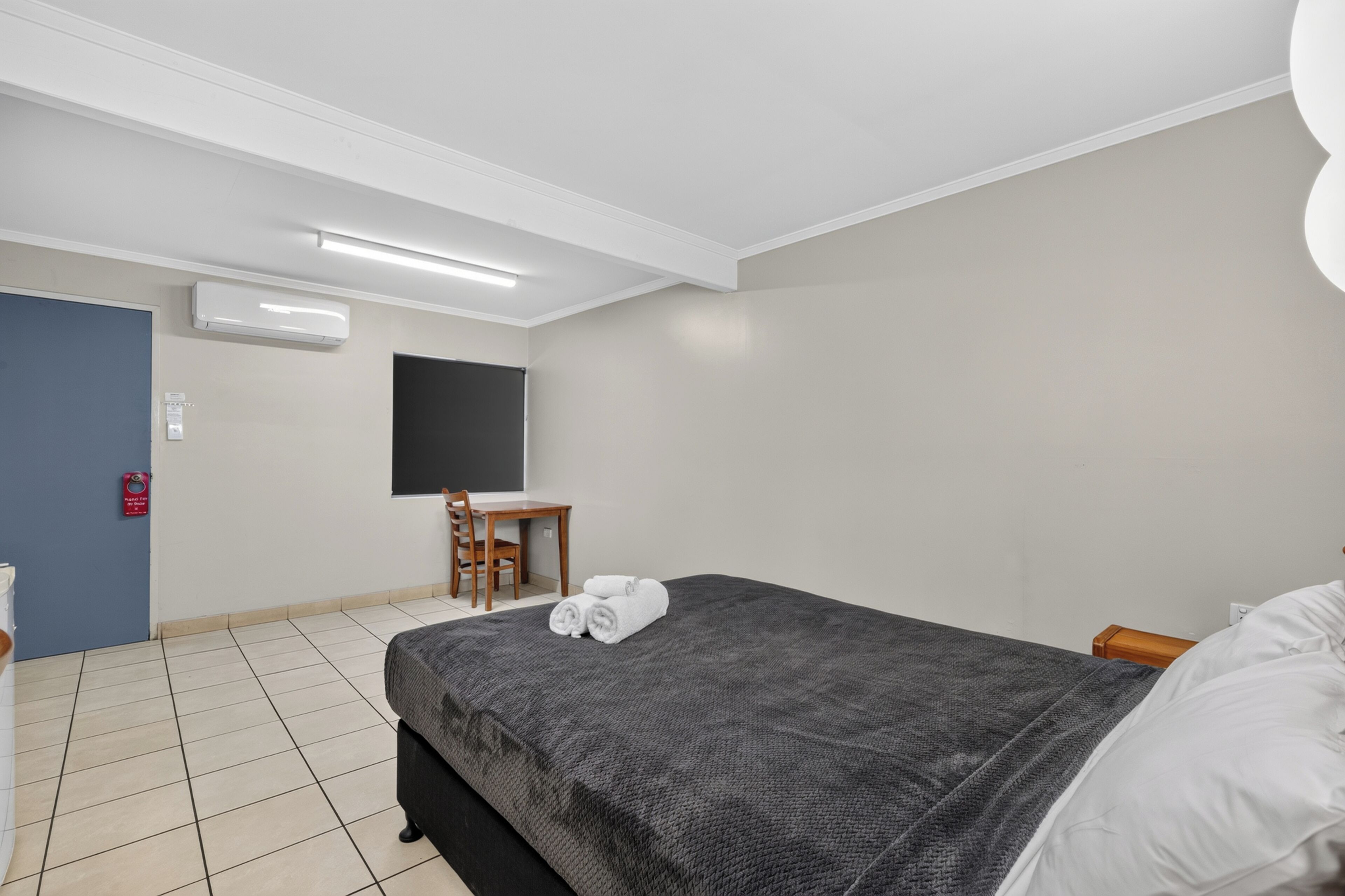 A hotel room with a bed, a desk, a chair, and a flat-screen TV.