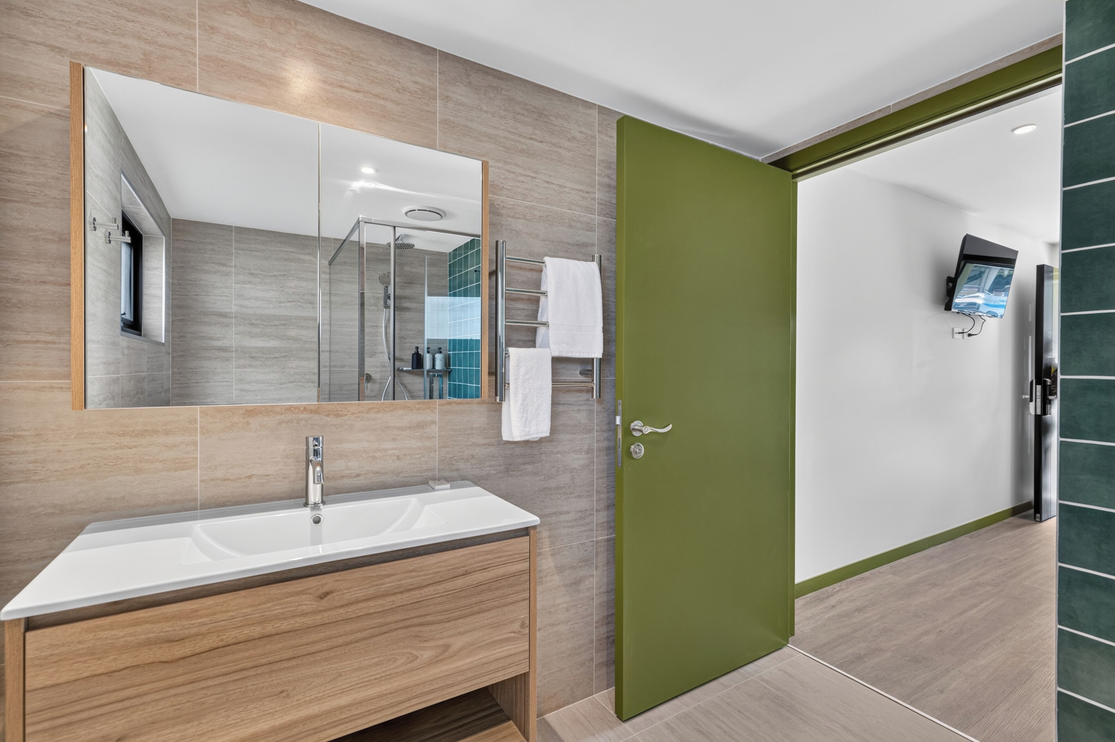 A modern bathroom with a large mirror, a sink, and a shower area.