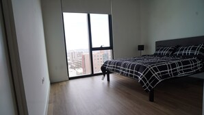 Un dormitorio con un ventanal grande, una cama con colcha a cuadros blanco y negro, y una lámpara de pie negra.