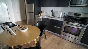 A modern kitchen with stainless steel appliances, a wooden dining table, and black chairs. - 2-bedroom apartment in soothing Phoenix with AC and fitness room (Phoenix)