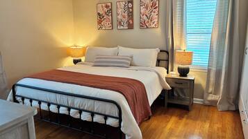 Una camera da letto con un letto, lampade da comodino, un tavolino e una finestra con tende, decorata con motivi floreali.