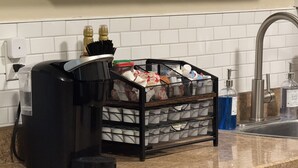 A kitchen with a coffee maker, a mesh organizer with various items, and a sink with hand soap. - Home Sweet Stillwater 4BR Near OSU (Stillwater)