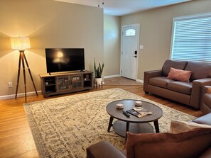 A living room with a television, a sofa, a coffee table, and a floor lamp.