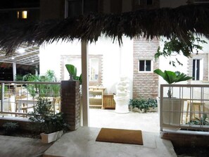 An outdoor area with a thatched roof, potted plants, and a white decorative structure. - Yara Hotel (Punta Cana)