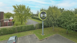 A B&B hotel sign with a parking area and a car.