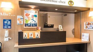 A reception desk with a 'Bienvenue chez B&B' sign, a map, and a directory.