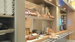 A breakfast buffet area with various food items and utensils.