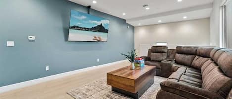 A living room with a sectional sofa, a coffee table, a rug, and a wall-mounted TV.