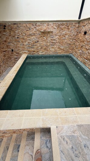 A rectangular swimming pool with a stone wall surrounding it. - 2-bedroom apartment in charming San Jerónimo with AC and private jacuzzi. (San Jerónimo)