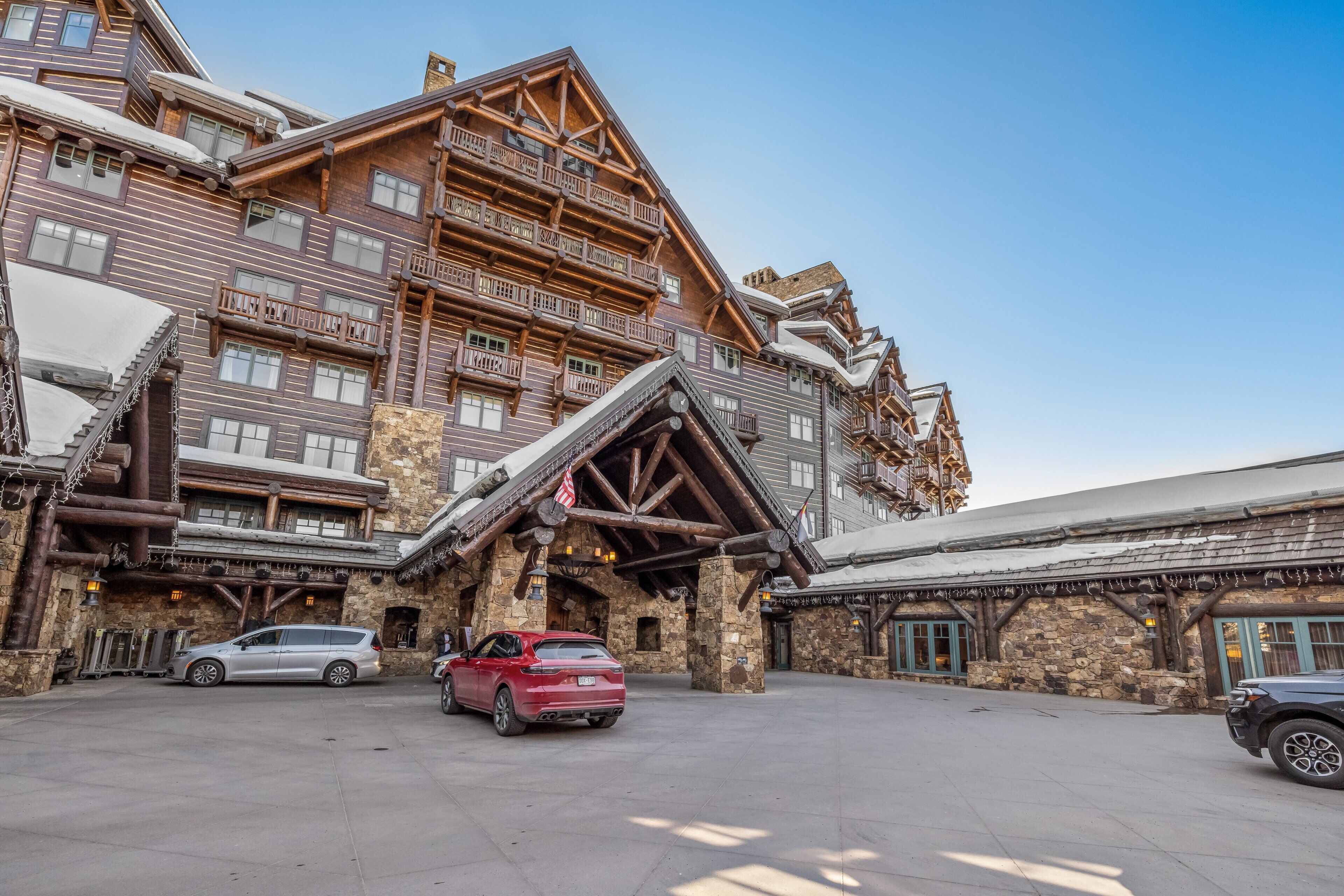 Un immeuble à plusieurs étages, doté d’une façade en pierre, de balcons en bois et d’une entrée aménagée comme un chalet de ski.
