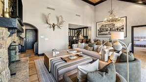 Un salon spacieux avec une cheminée, un grand canapé et un lustre.