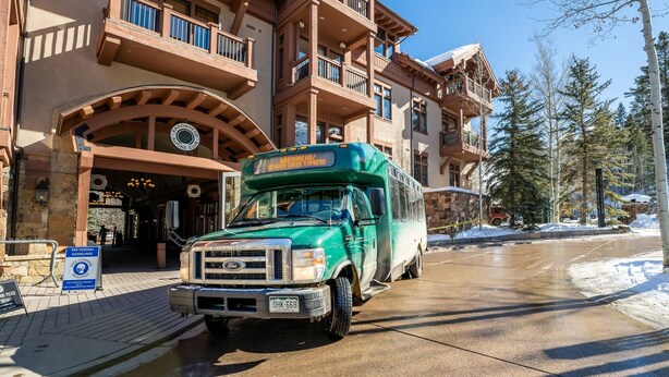 Un autobus vert est garé devant un bâtiment sur lequel on peut lire l’inscription : « Arrowhead Alpine Club ».