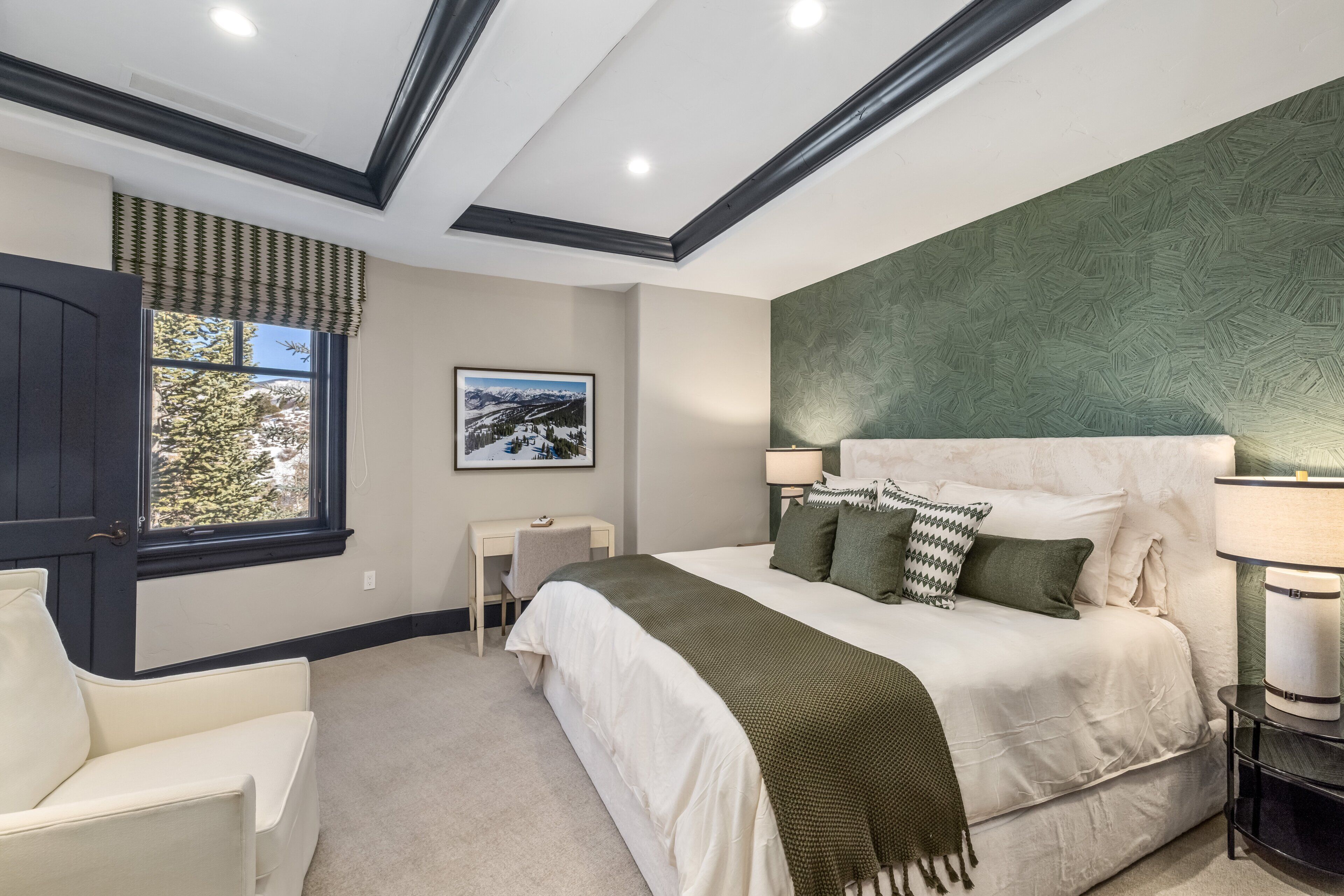 A bedroom with a bed, a desk, a chair, a window, and a picture on the wall.