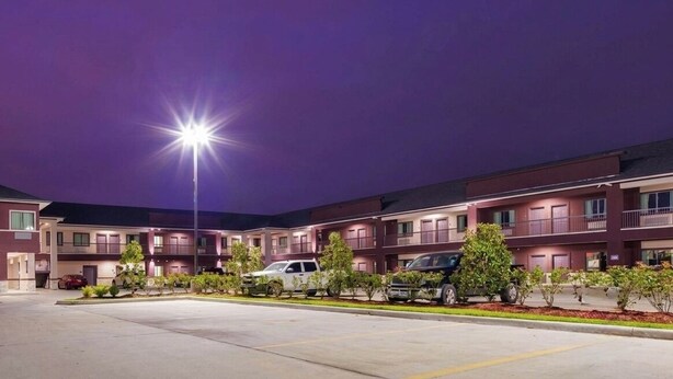 A multi-story hotel with a parking lot and a well-lit entrance.