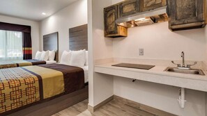 A hotel room with a bed, a bedside table, a built-in shelf, and a window with curtains.