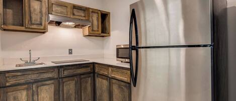 A kitchen with wooden cabinets, a stainless steel refrigerator, and a built-in oven.