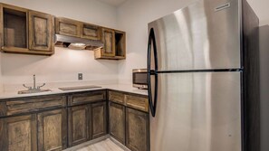 Una cocina con armarios de madera, un refrigerador de acero inoxidable y un horno empotrado.